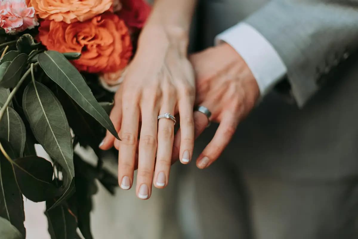 Mãos de um casal exibindo alianças